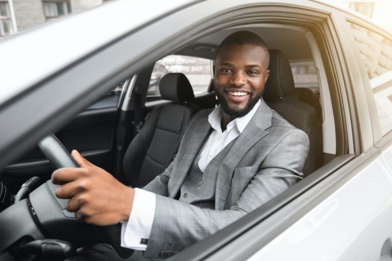 Handsome smiling black businessman driving luxury car